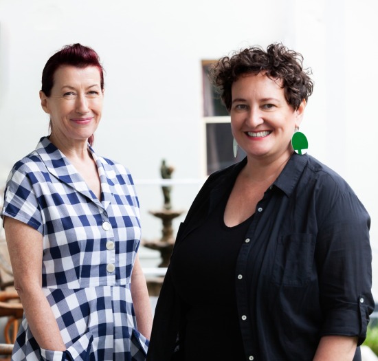 CEO Dominique Antarakis and Strategy Consultant Jan Chisholm standing on a verandah smiling at the camera