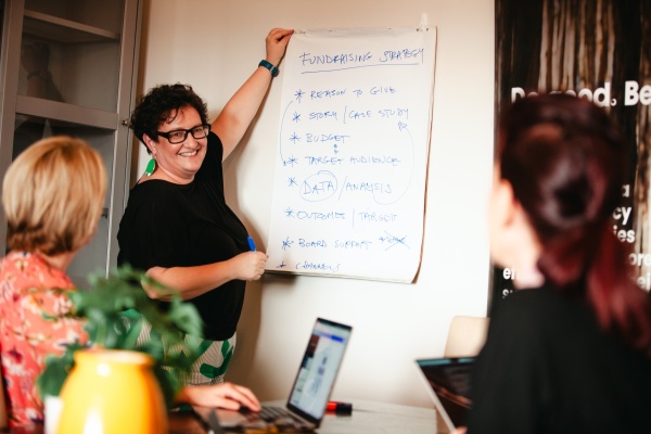 Dominique hosting a training session. She writes notes on paper on the wall as others watch.