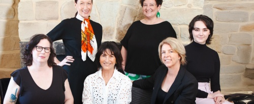 Change&Co team sitting on a couch in front of a stone wall smiling at camera
