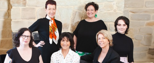 Change&Co team sitting on a couch in front of a stone wall smiling at camera